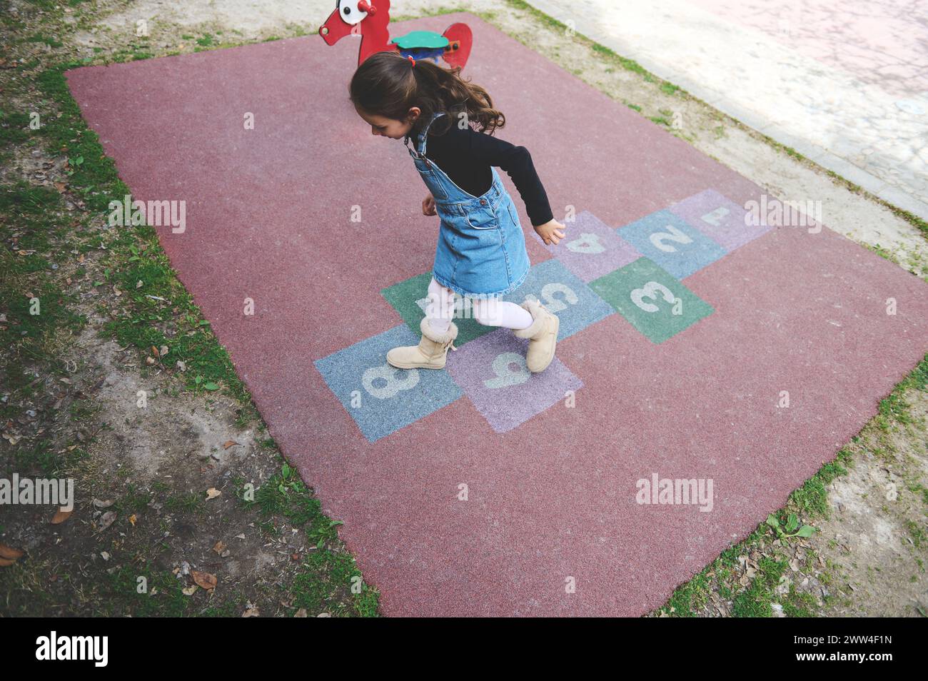 Overhead view of a little child girl jumping on squares, playing hopscotch on the school playground. Street children's games in classics. Popular stre Stock Photo