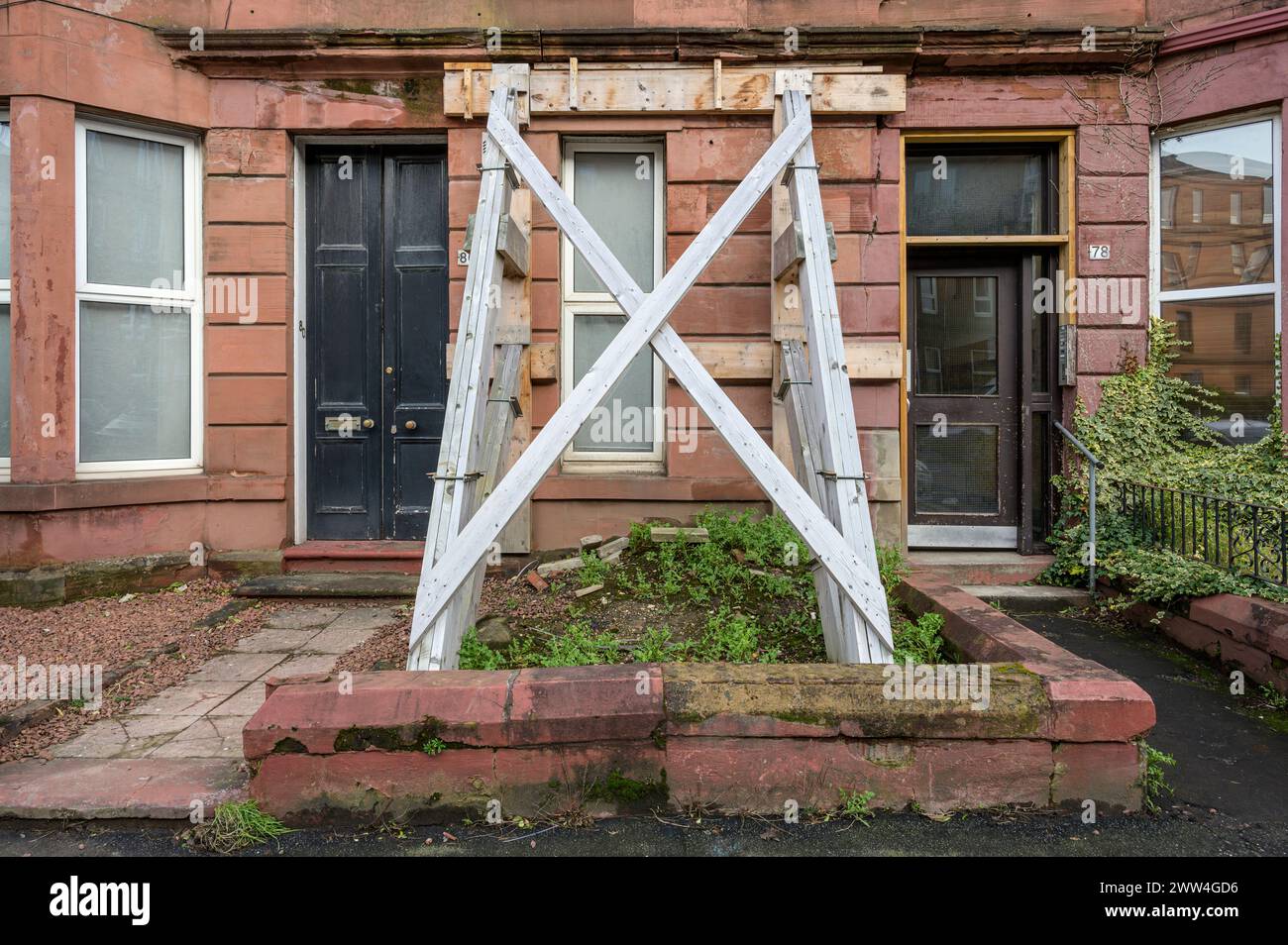 A damaged tenement block supported on the ground floor by an extenal structural timber brace, Glasgow, Scotland, UK, Europe Stock Photo