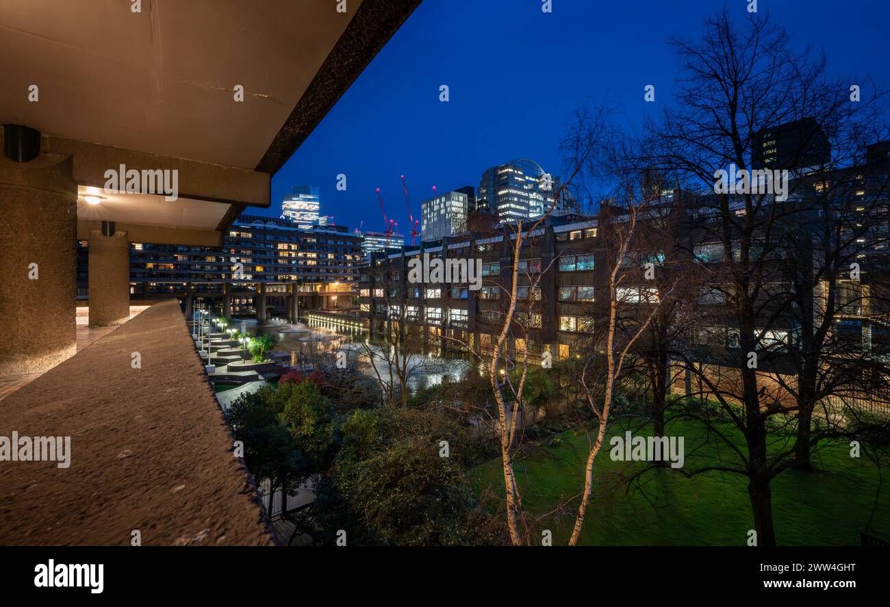 London, UK: Night view of the Barbican Estate in the City of London with garden and lake. A prominent example of Brutalist architecture. Stock Photo
