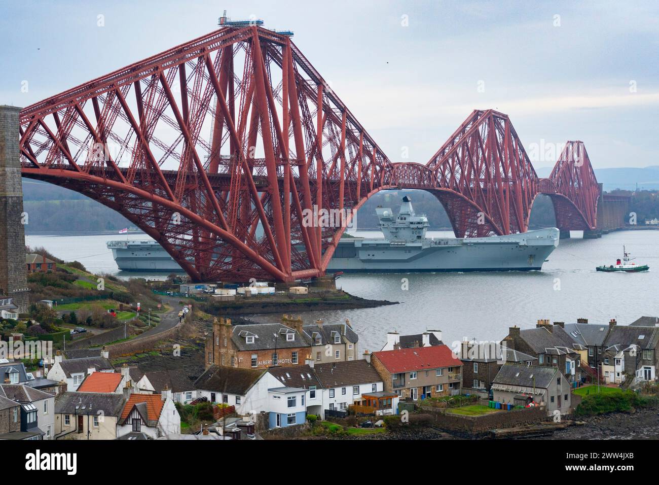 North Queensferry, Scotland, UK. 21st March, 2024. Royal Navy aircraft carrier  HMS Queen Elizabeth sails under the Forth Bridge at low tide at North Stock Photo