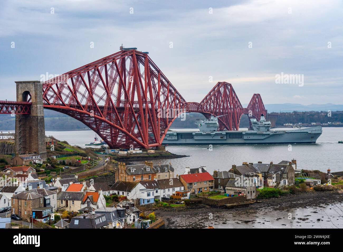 North Queensferry, Scotland, UK. 21st March, 2024. Royal Navy aircraft carrier  HMS Queen Elizabeth sails under the Forth Bridge at low tide at North Stock Photo