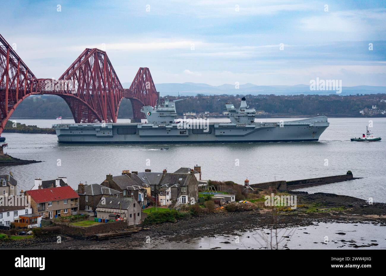 North Queensferry, Scotland, UK. 21st March, 2024. Royal Navy aircraft carrier  HMS Queen Elizabeth sails under the Forth Bridge at low tide at North Stock Photo