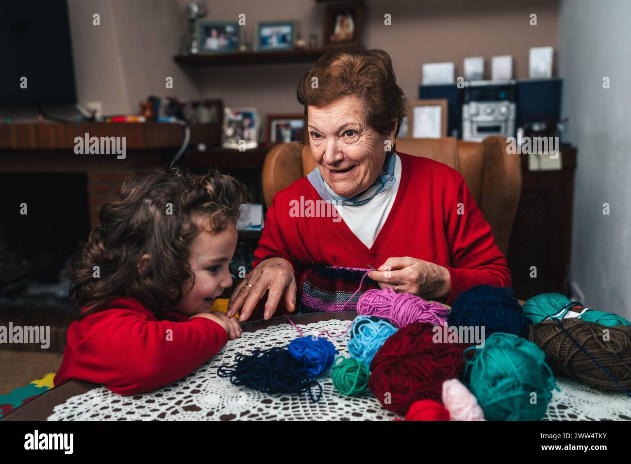 horizontal photo of grandmother and grandson having fun while sewing with a needle in the living room at home, relaxed and happy Stock Photo