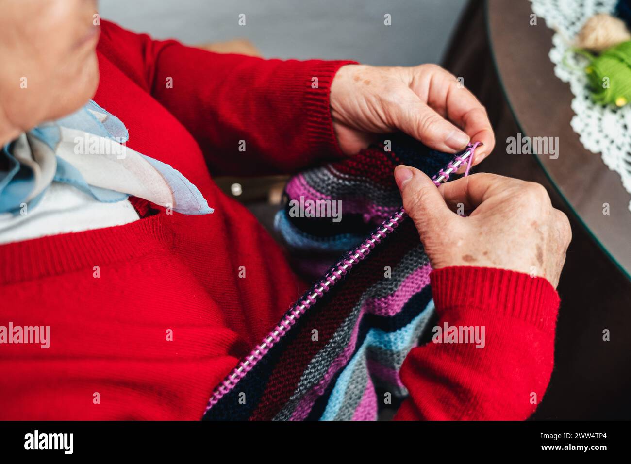 low angle horizontal portrait of senior woman's hands sewing clothes by