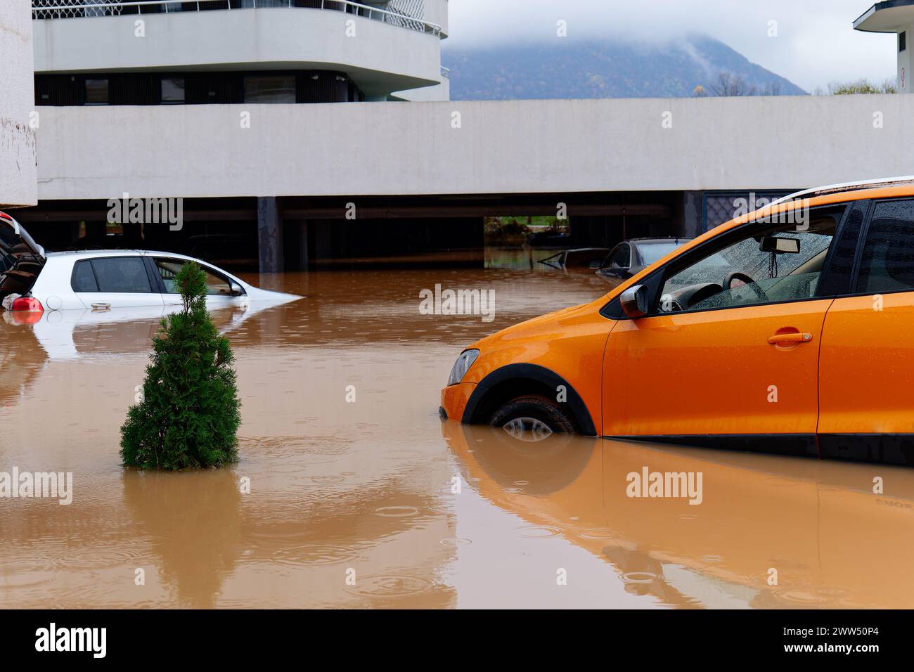 Torrential rain causes flash floods in the city area. Cars under water in the condominium parking lot. Damaged cars caused by heavy rainfall Stock Photo