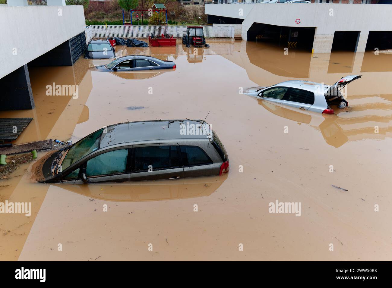 Torrential rain causes flash floods in the city area. Cars under water in the condominium parking lot. Damaged cars caused by heavy rainfall Stock Photo