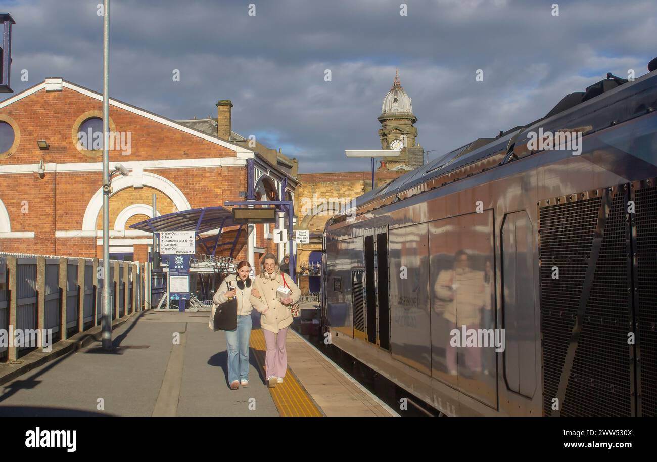 3 November 23 Commuters wa;k the platform in Scarborough Railway Station, part of the northern rail network. The ancient clock tower is in the backgro Stock Photo