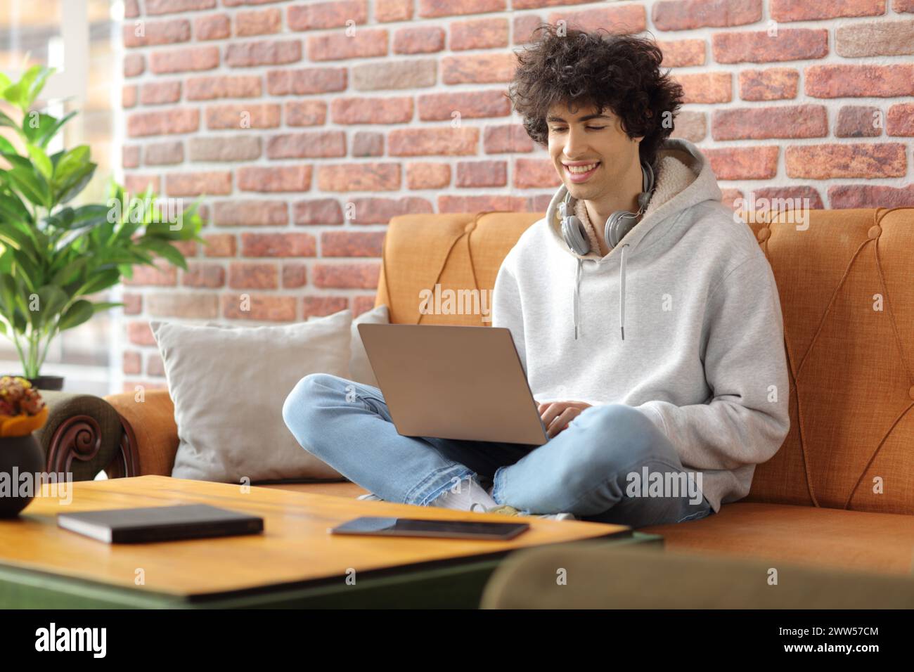 Student with headphones sitting in a cafe and using a laptop computer Stock Photo