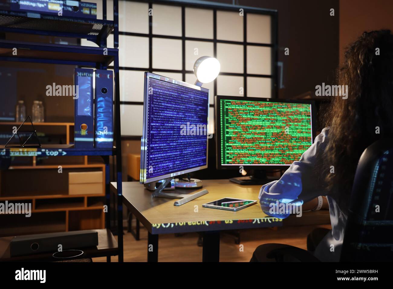 Female programmer working with computer monitors in office at night ...