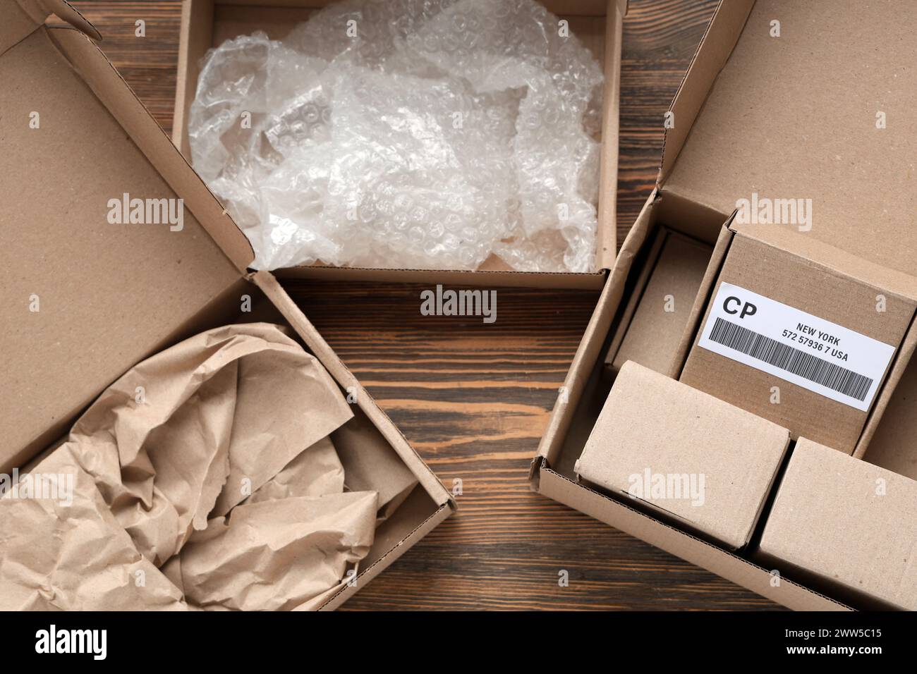 Cardboard packages with boxes, packing paper and bubble wrap on wooden table Stock Photo