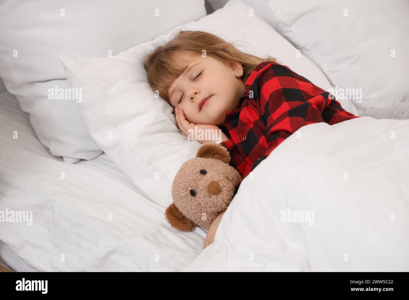 Adorable little girl in pajamas with teddy bear sleeping in bed Stock ...