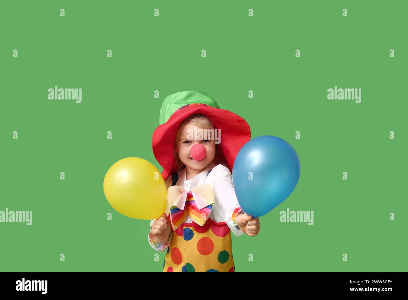 Cute girl in clown costume with balloons on green background Stock ...
