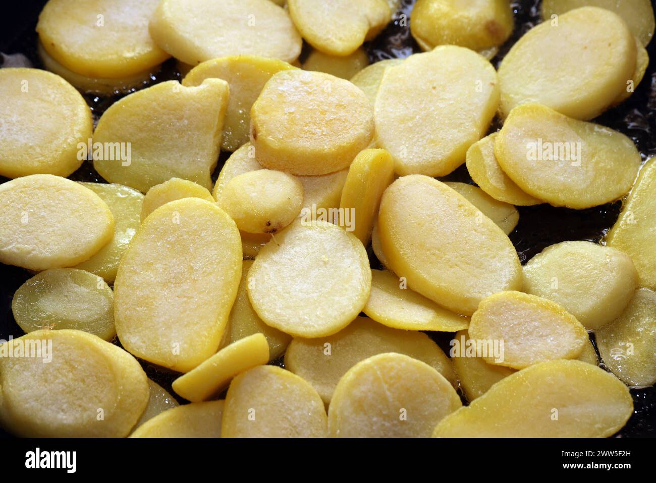 Deftige Mahlzeiten aus der Kartoffel Rohe Kartoffeln in heißem Öl während der Zubereitung zu deftigen Bratkartoffeln. *** Hearty meals from the potato Raw potatoes in hot oil during preparation to make hearty fried potatoes Stock Photo