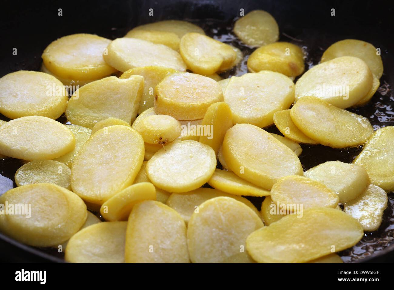 Deftige Mahlzeiten aus der Kartoffel Rohe Kartoffeln in heißem Öl während der Zubereitung zu deftigen Bratkartoffeln. *** Hearty meals from the potato Raw potatoes in hot oil during preparation to make hearty fried potatoes Stock Photo