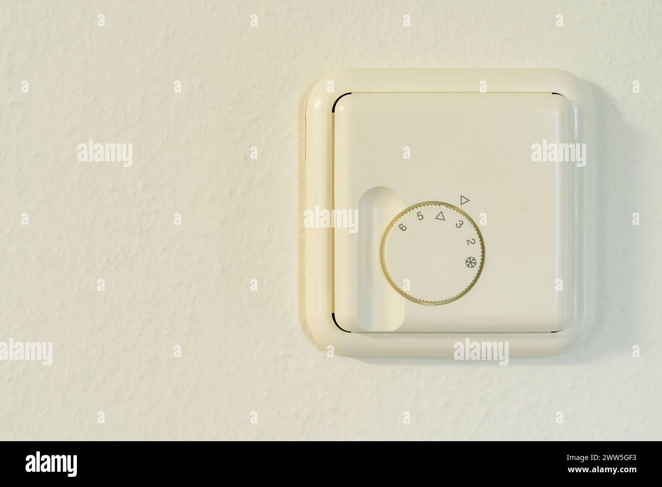 Thermostat adjustment device in white, mounted on a wall, with numbers, for regulating the room temperature. Stock Photo