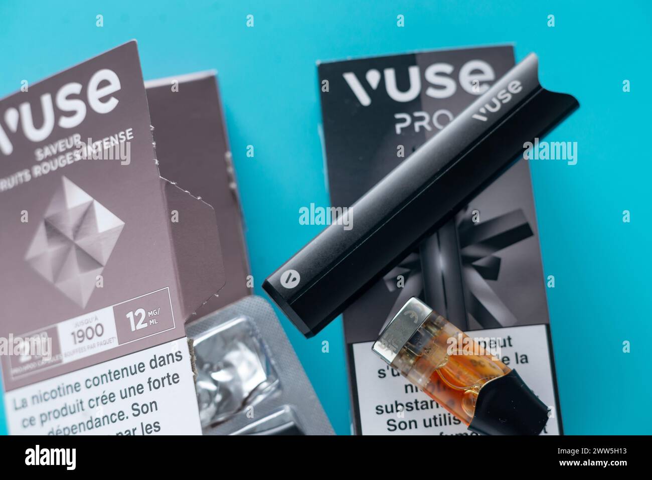 Caen, France - March 18, 2024: A vape and a box of vape juice sit on a blue surface. The box is labeled with the brand name VUSE Pro Stock Photo