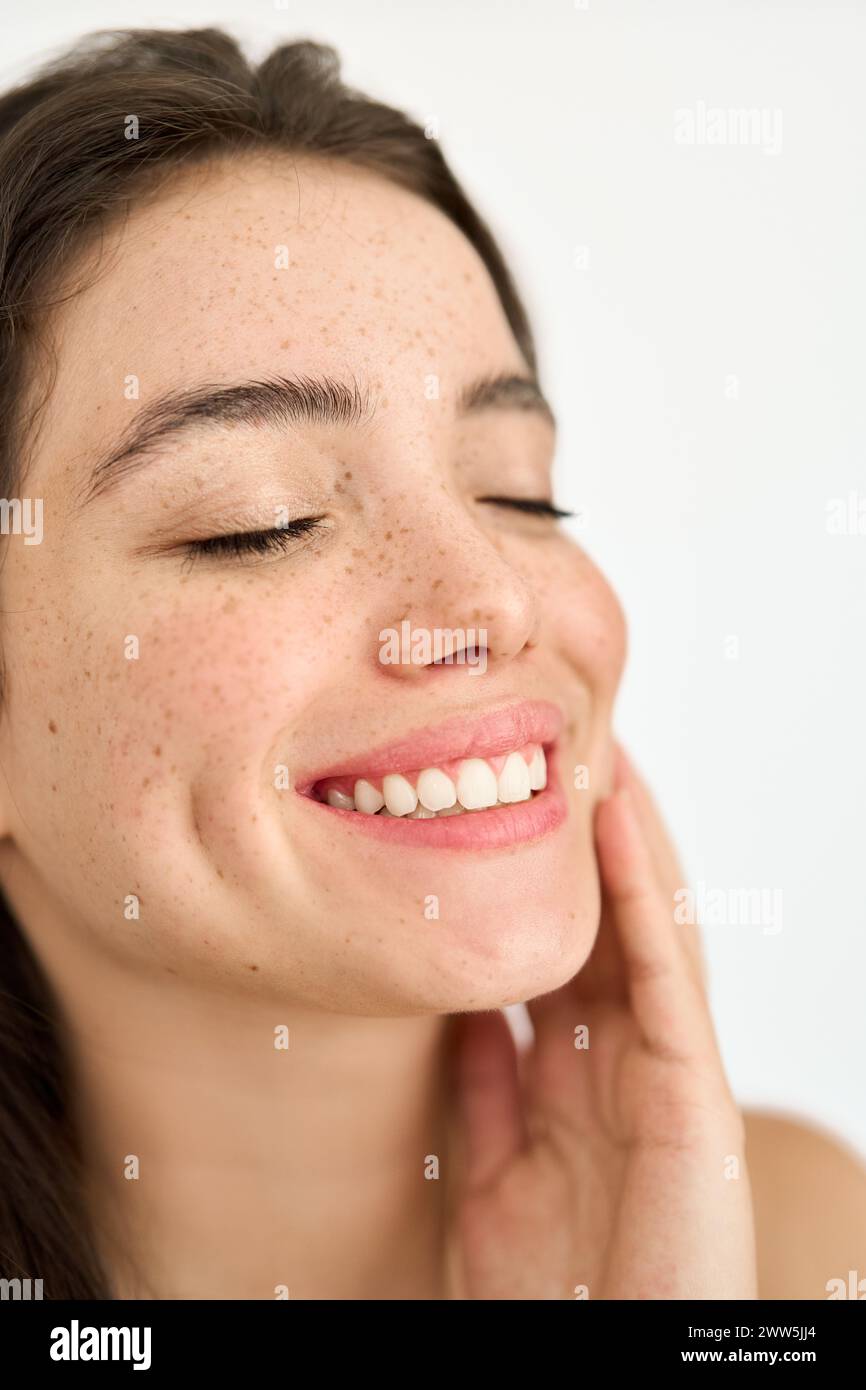 Happy brunette Latin girl with freckles touching face isolate on white. Vertical Stock Photo
