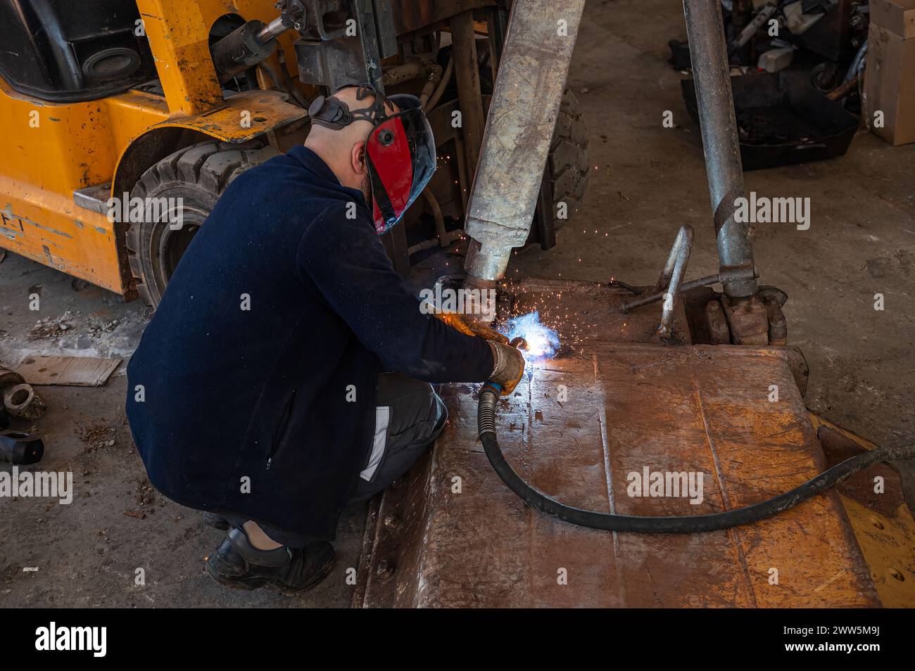 Industrial welder with torch and helmet welding metal profiles. Stock Photo