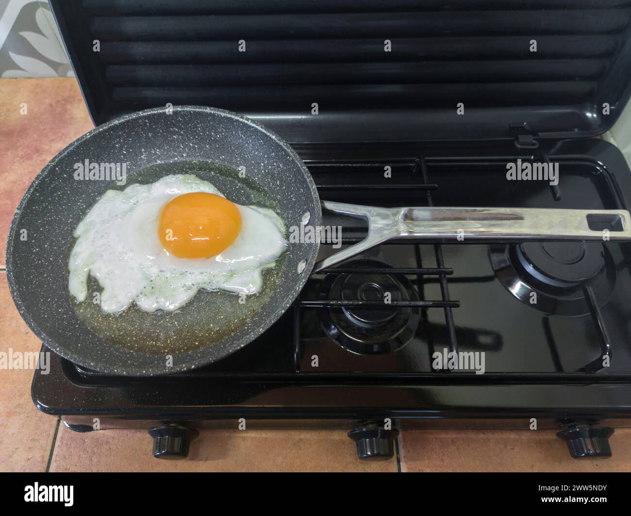 Big goose egg frying in a pan on a gas stove. Overhead view Stock Photo