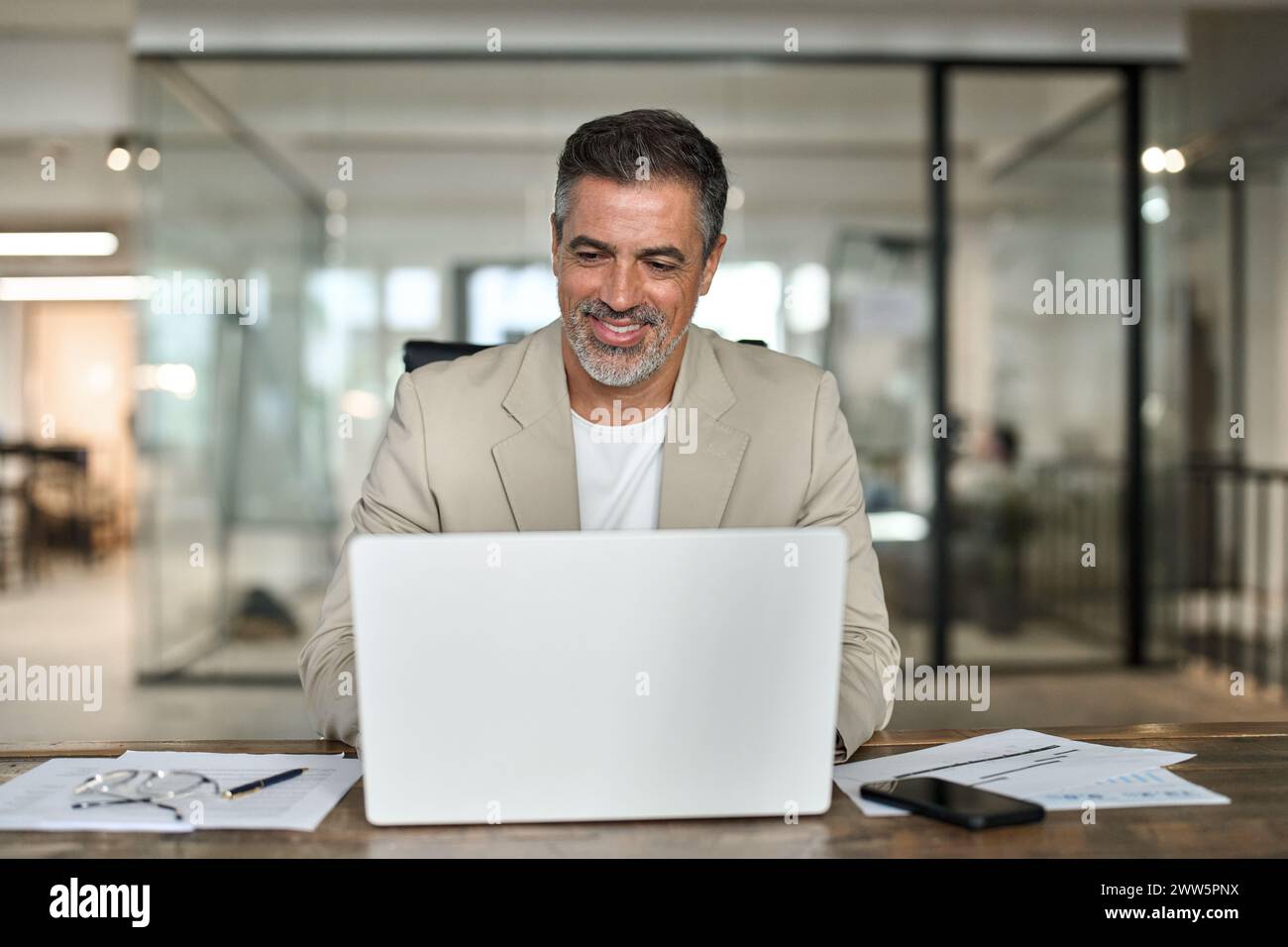 Happy middle aged professional business man using computer working at desk. Stock Photo
