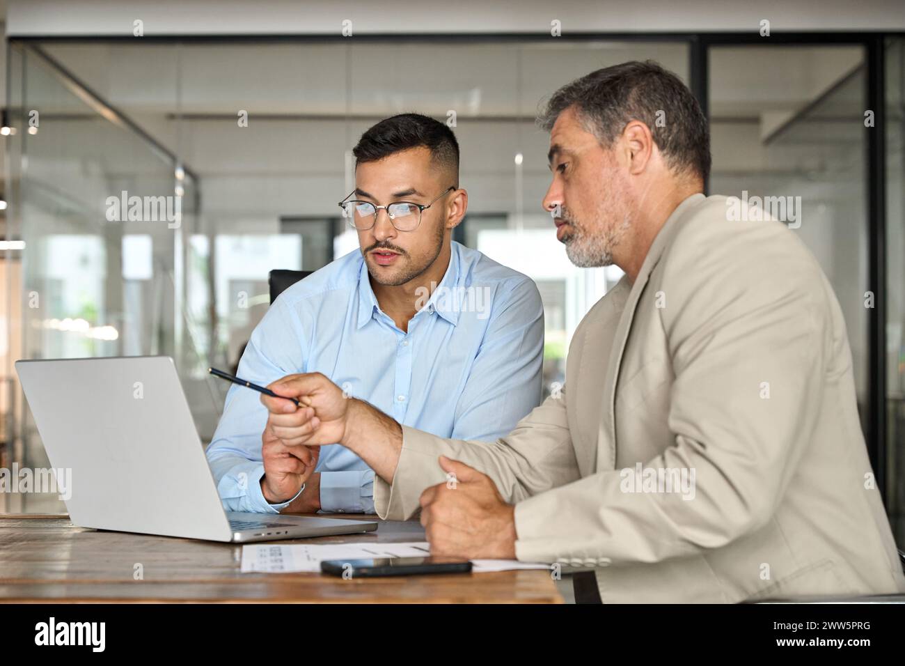 Two busy business men working using laptop computer in office. Stock Photo
