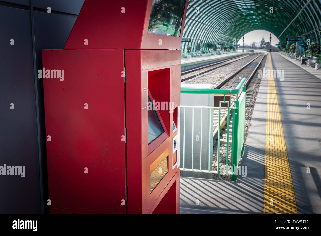 At a bustling train station, a modern, red ticket vending machine stands ready to serve the needs of commuters. It's a typical sight in today's fast-p Stock Photo