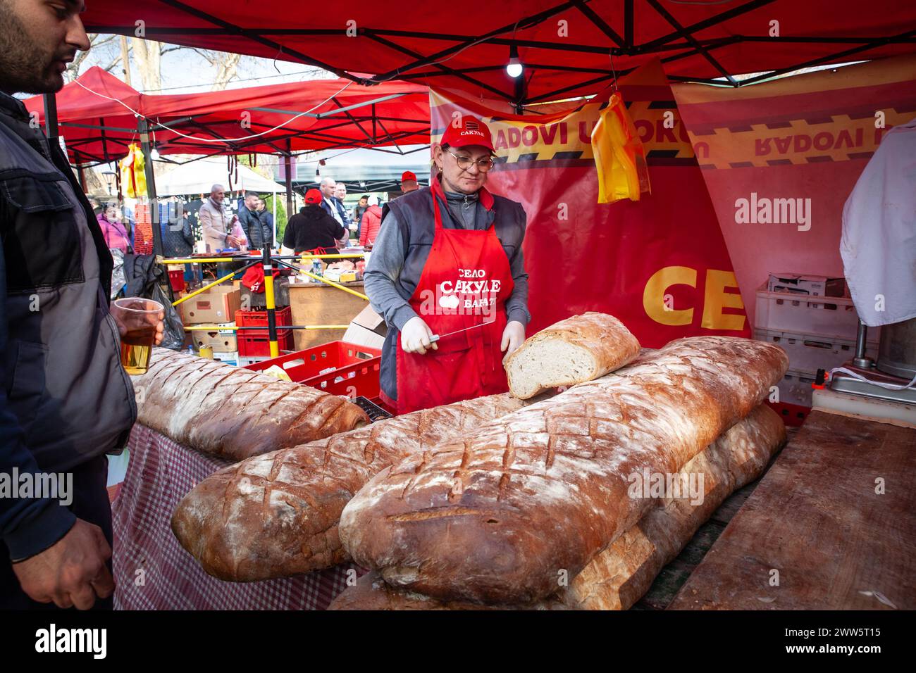 Picture of a local bread seller, a baker, with giant loaves of bread