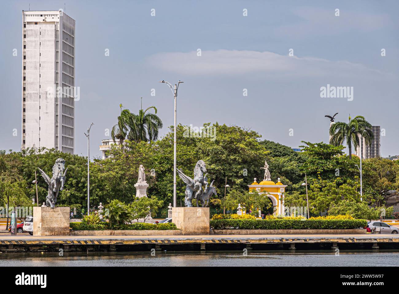Cartagena, Colombia - July 25, 2023: Double Pegasus statues at end of old town dock with green Centenario Park behind. Yellow monumental gate into the Stock Photo