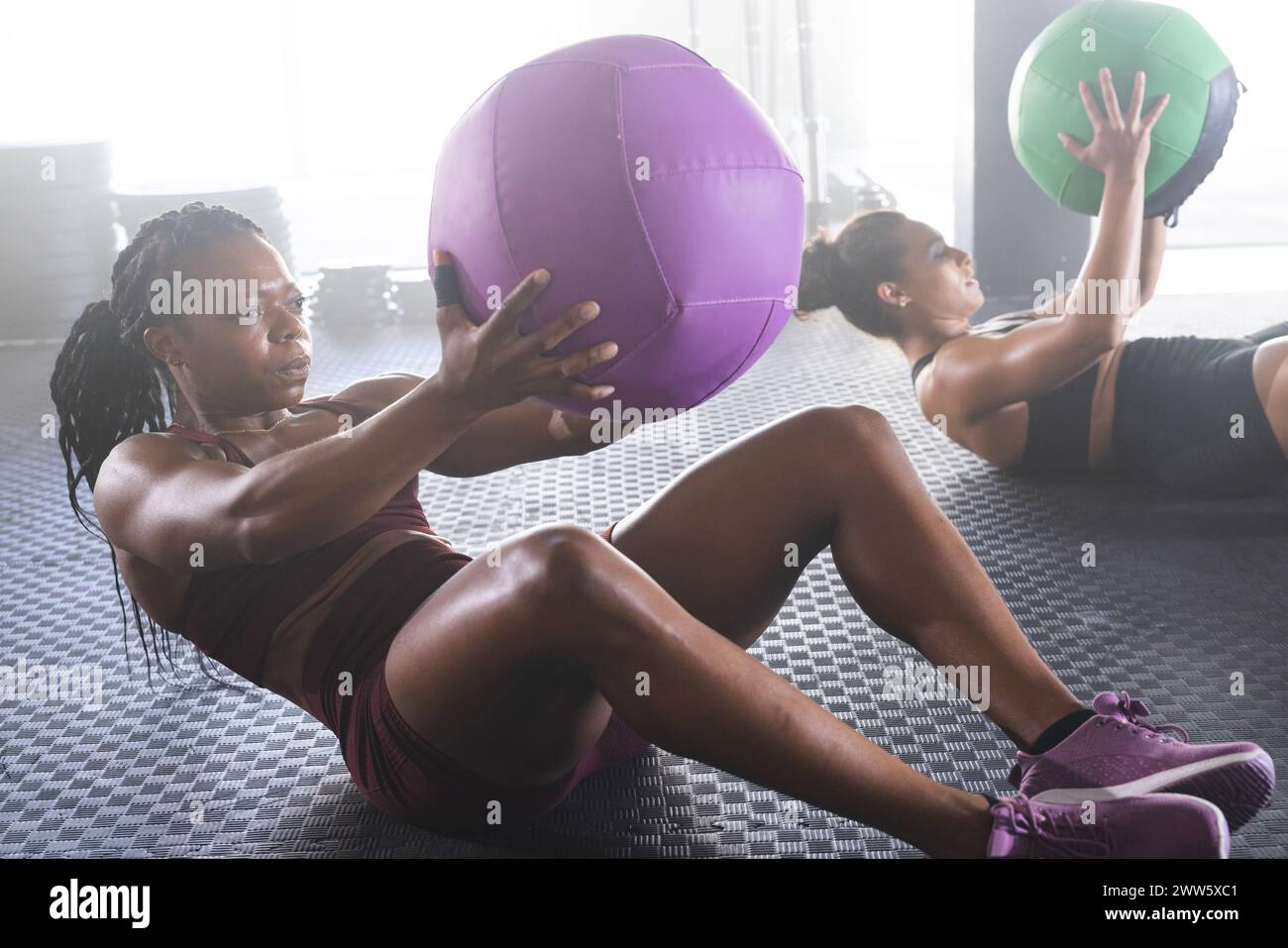 Two women engage in a gym workout with medicine balls in a gym Stock Photo