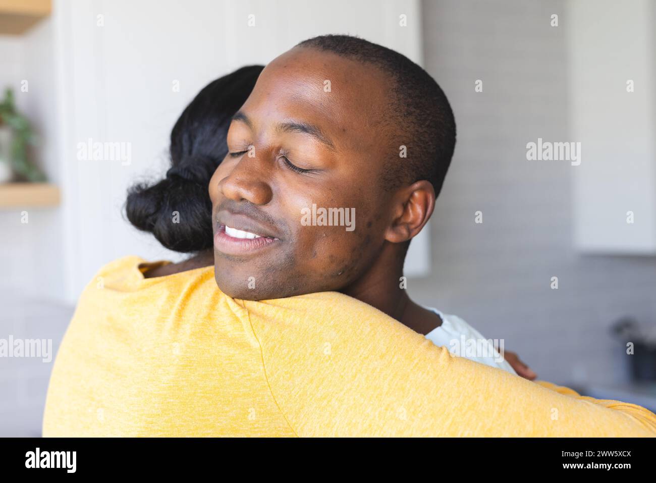 African American couple shares a warm embrace at home in the kitchen Stock Photo