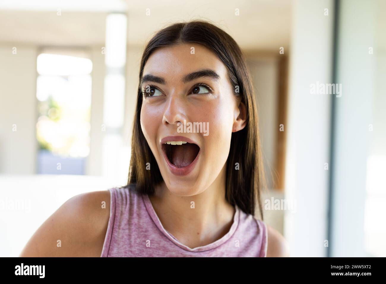 A young Caucasian brunette woman expresses excitement at home Stock Photo