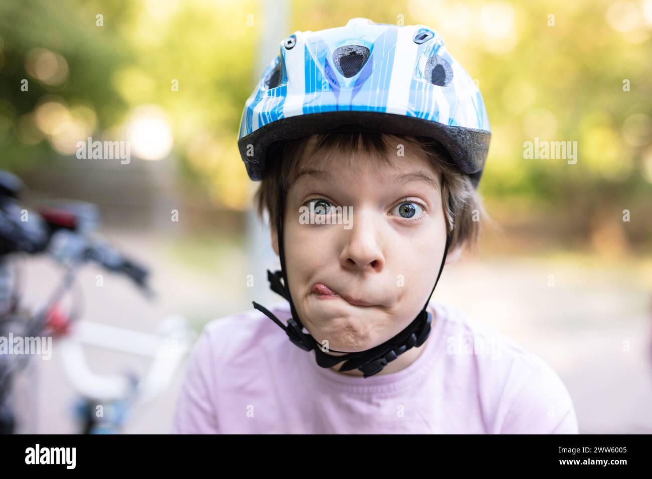 Young boy in helmet making faces outdoors Stock Photo