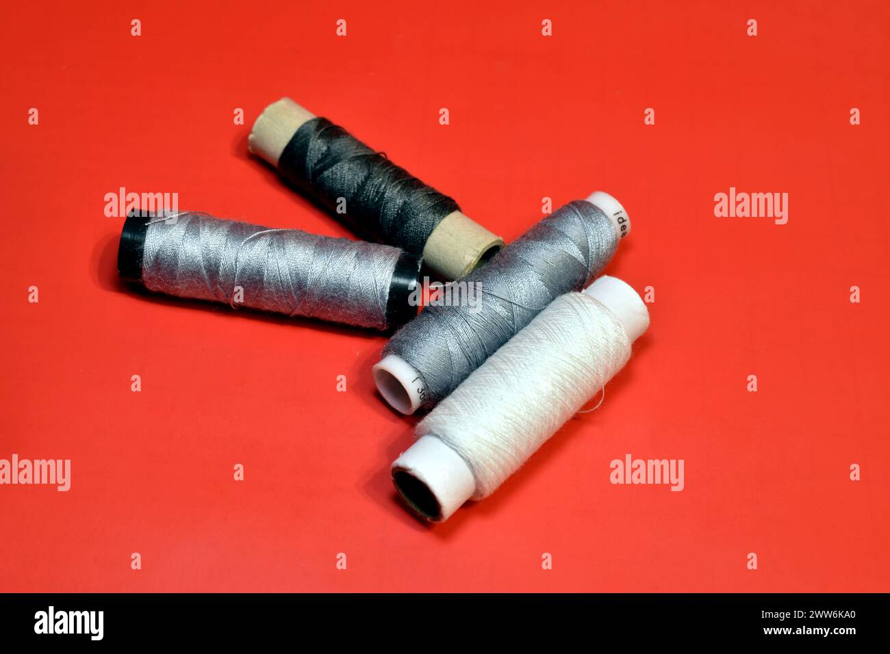 Spools of thread for working on a sewing machine lie on a red background. Stock Photo