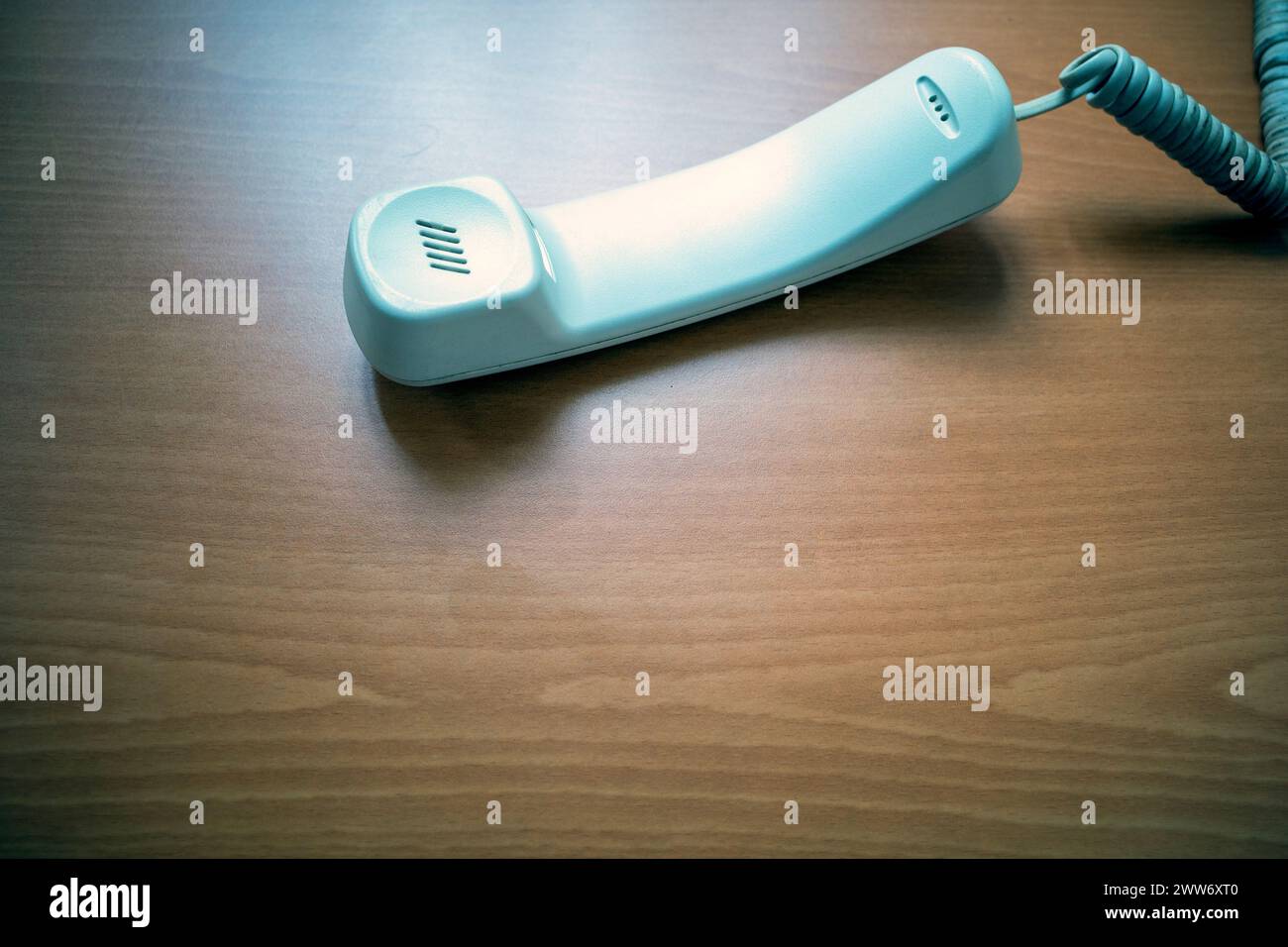White handset of landline phone on wooden table. Telecomunication concept background. Stock Photo