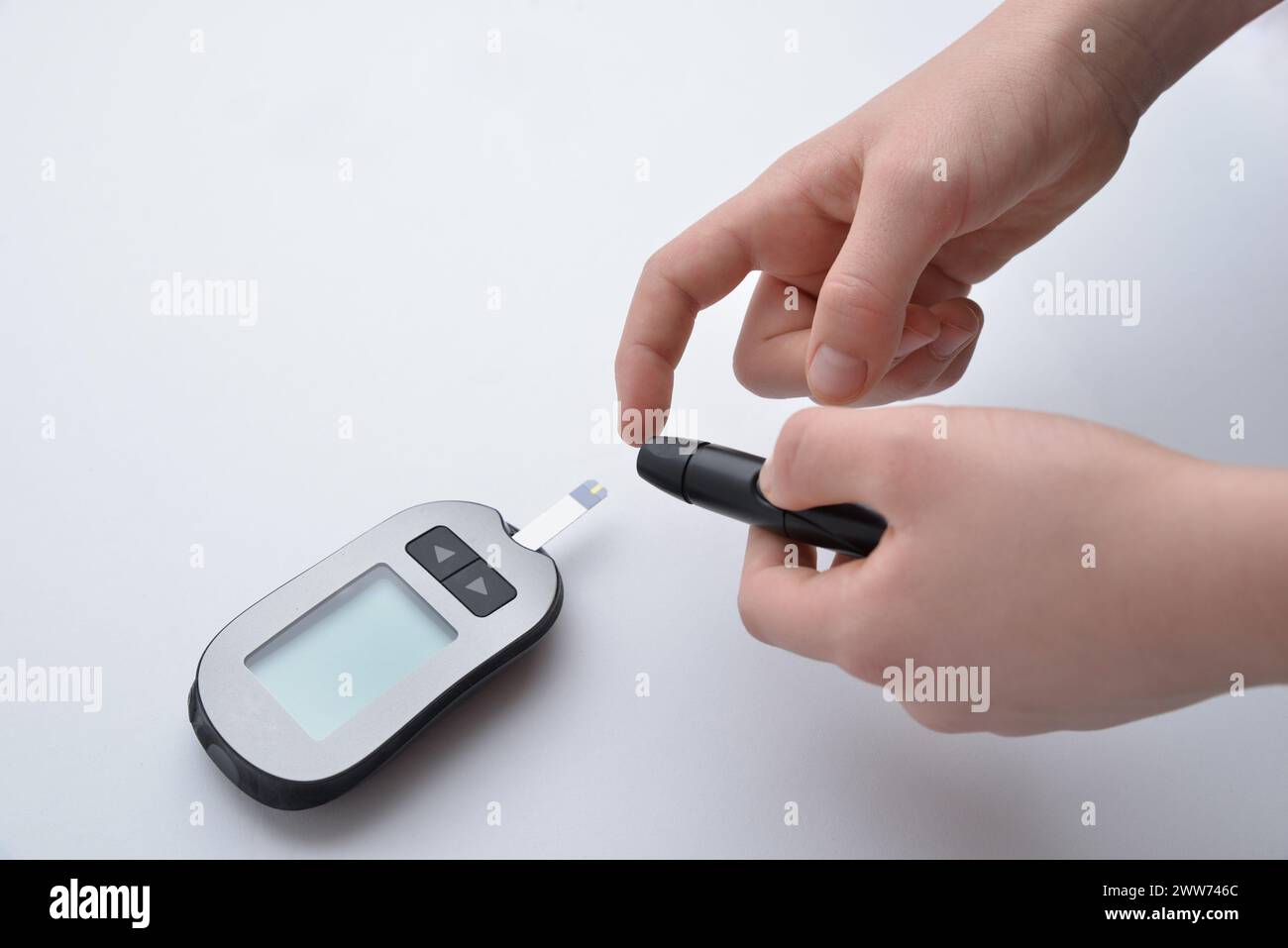 Pricking finger to measure blood sugar level using devices and strips. Highlighting the importance of diabetes management, health monitoring, and medi Stock Photo