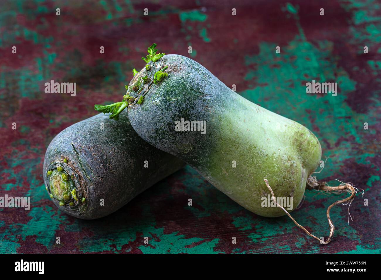 Two large vegetables on top of each other close-up on old green plank. Stock Photo