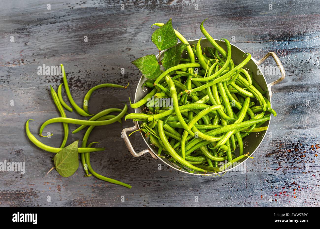Green beans in an old colander on an old gray board. Stock Photo