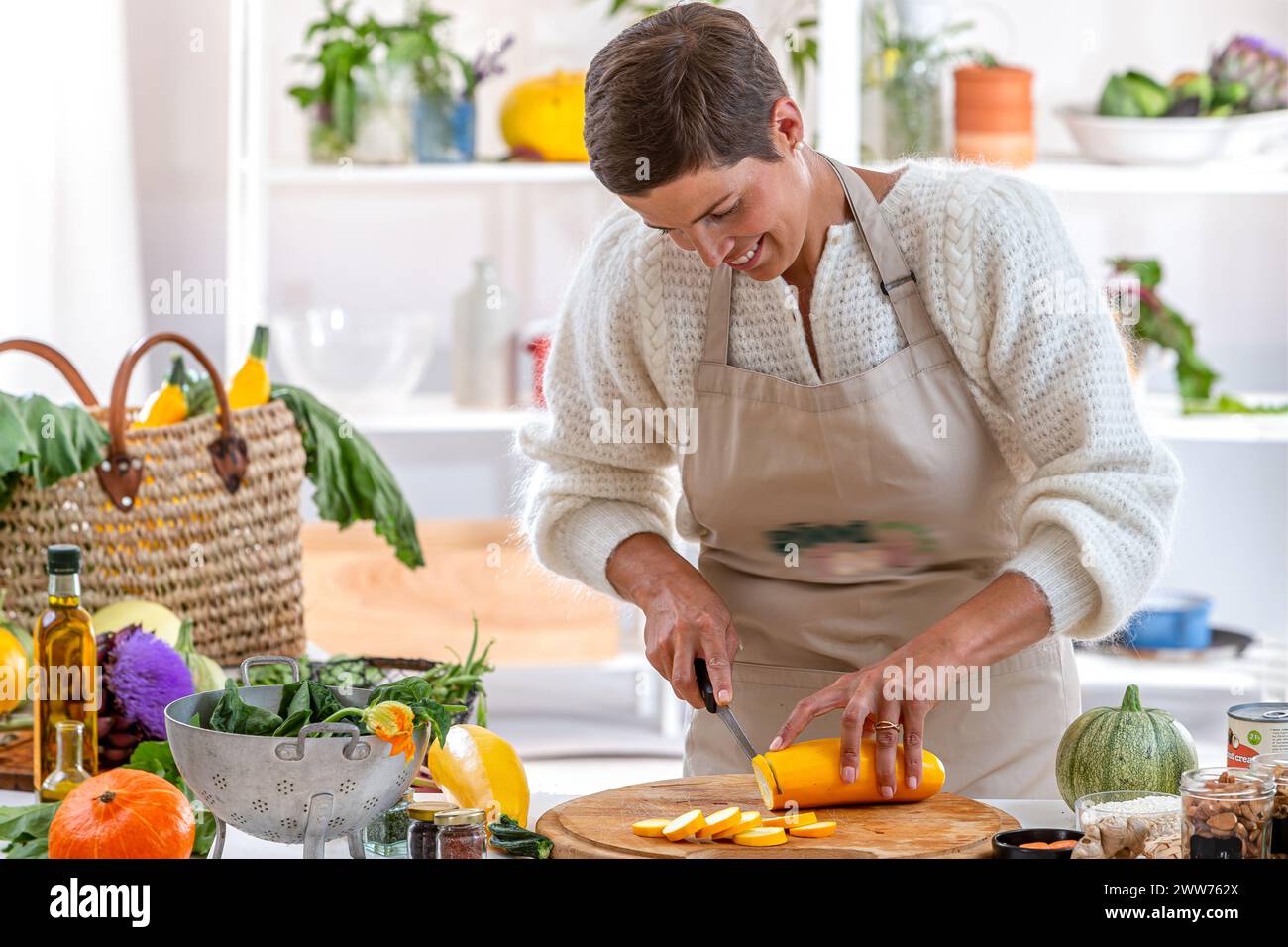 Young woman in her kitchen surrounded by organic vegetables. Stock Photo