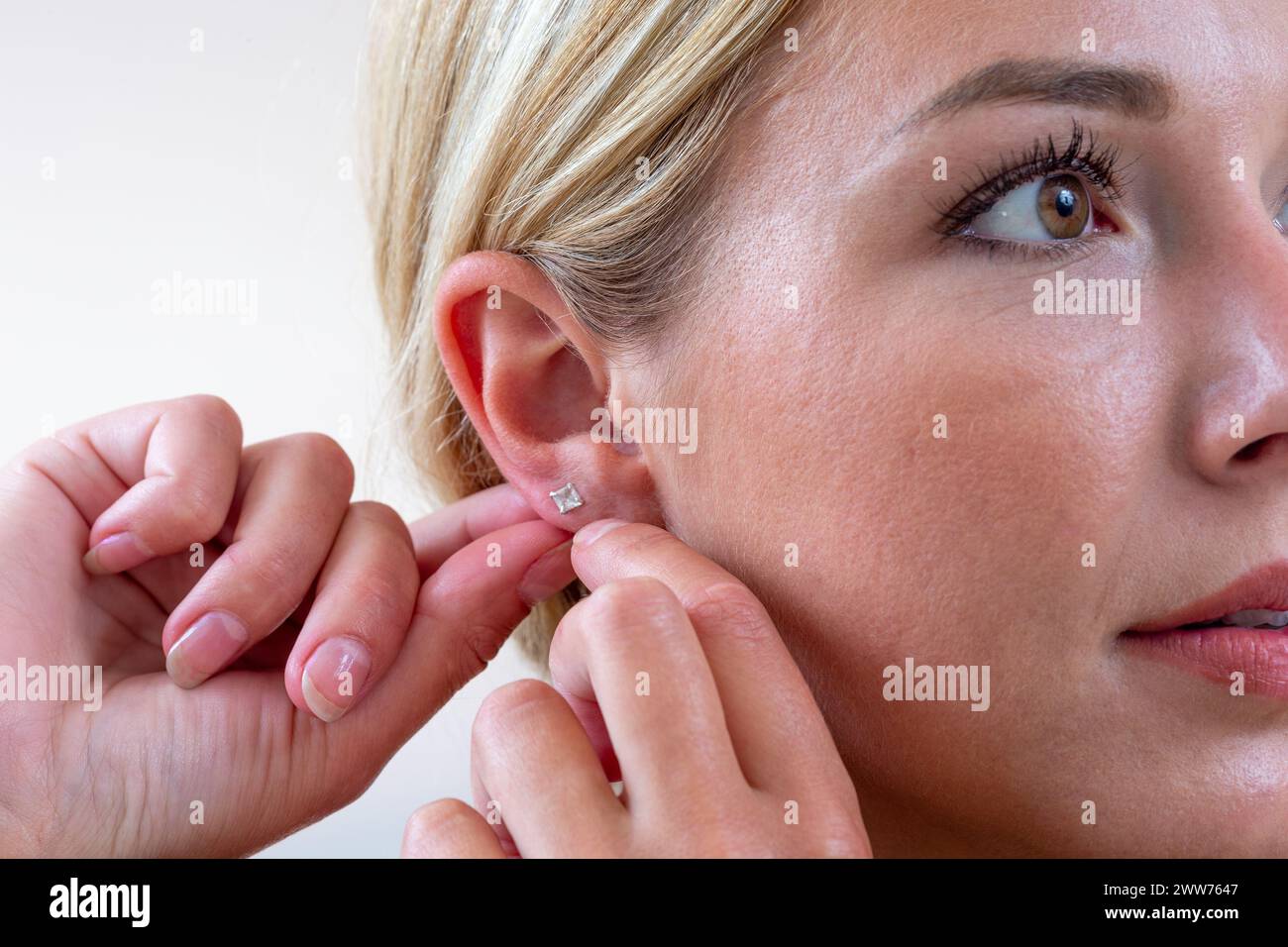 Woman hanging an earring. Stock Photo