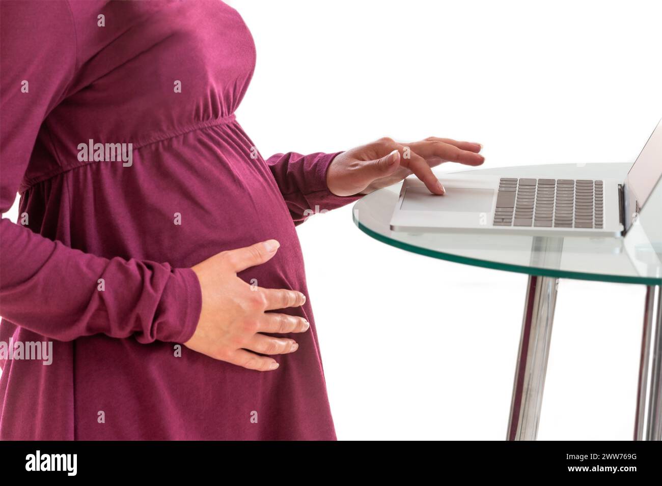 Close up-Hand on stomach, other on computer keyboard. Stock Photo