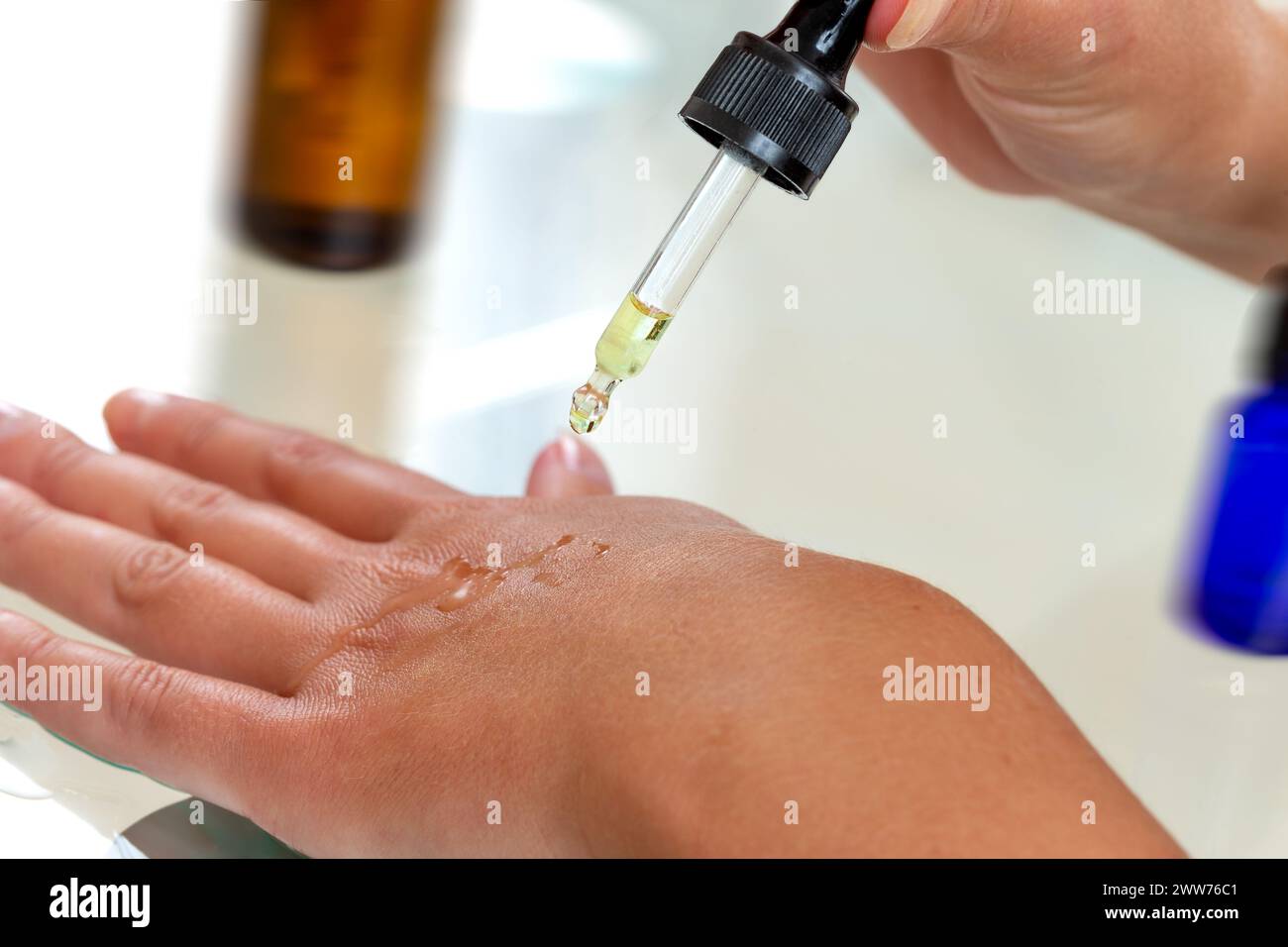 Close-up pipette dropping a drop of essential oil on the hand. Stock Photo