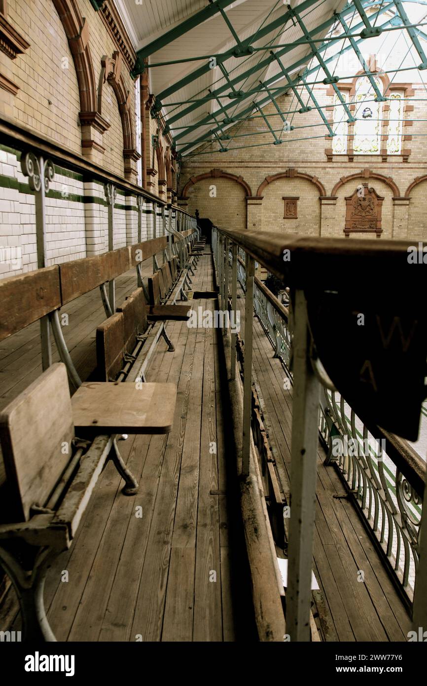 Old Woden seating on the upper balcony level at the disused and empty Victoria Baths swimming pool, Manchester, UK Stock Photo