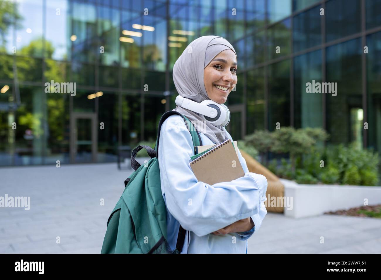 A contemporary student carrying a backpack and books walks in front of ...