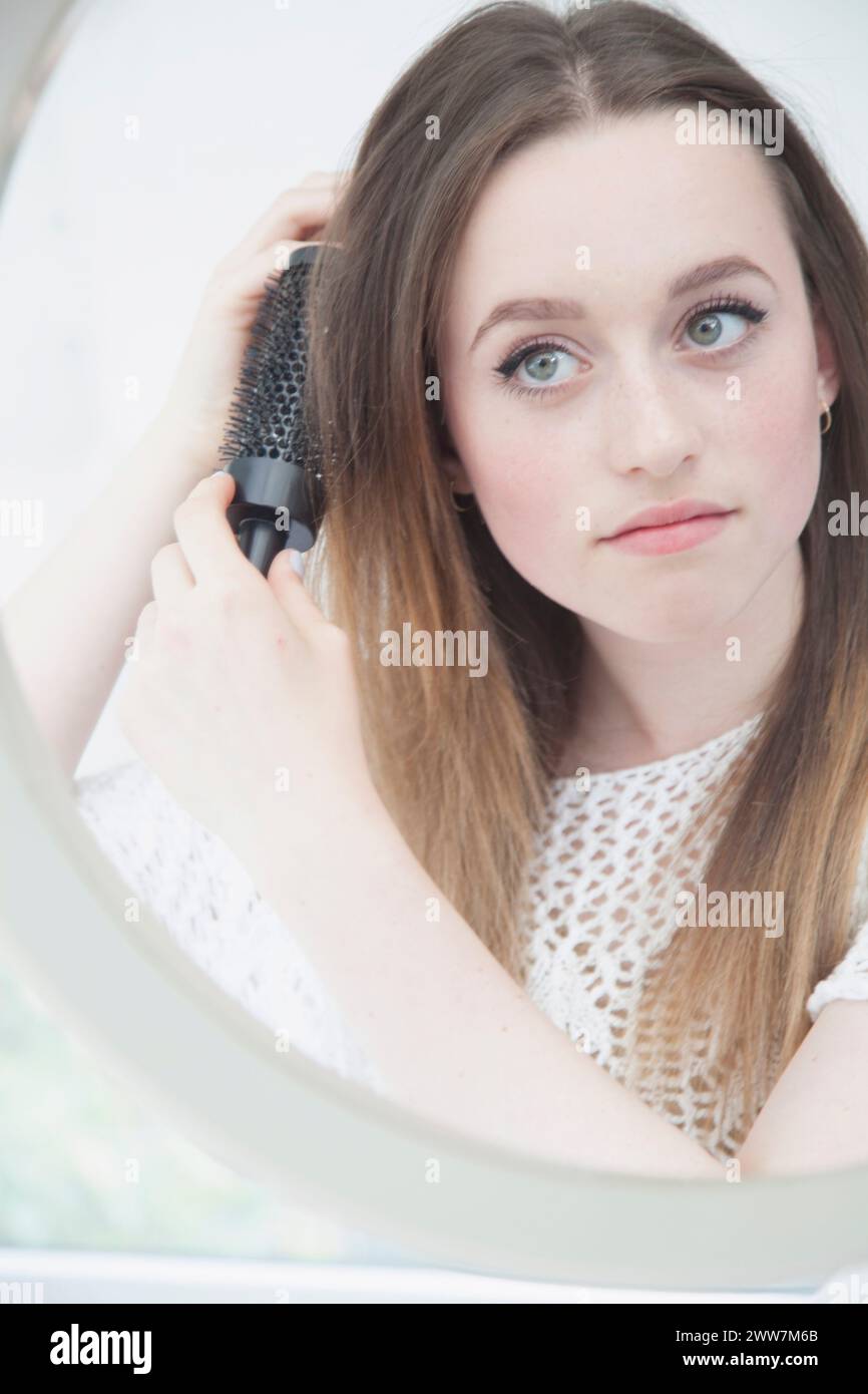 Teenage Girl Looking in Mirror Brushing her Hair Stock Photo - Alamy