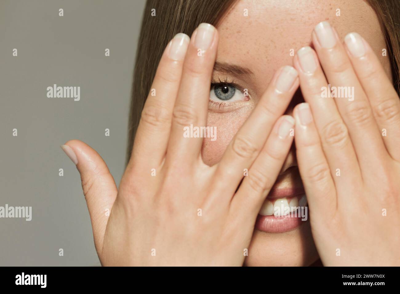 Woman with Hands over Eyes Smiling Stock Photo