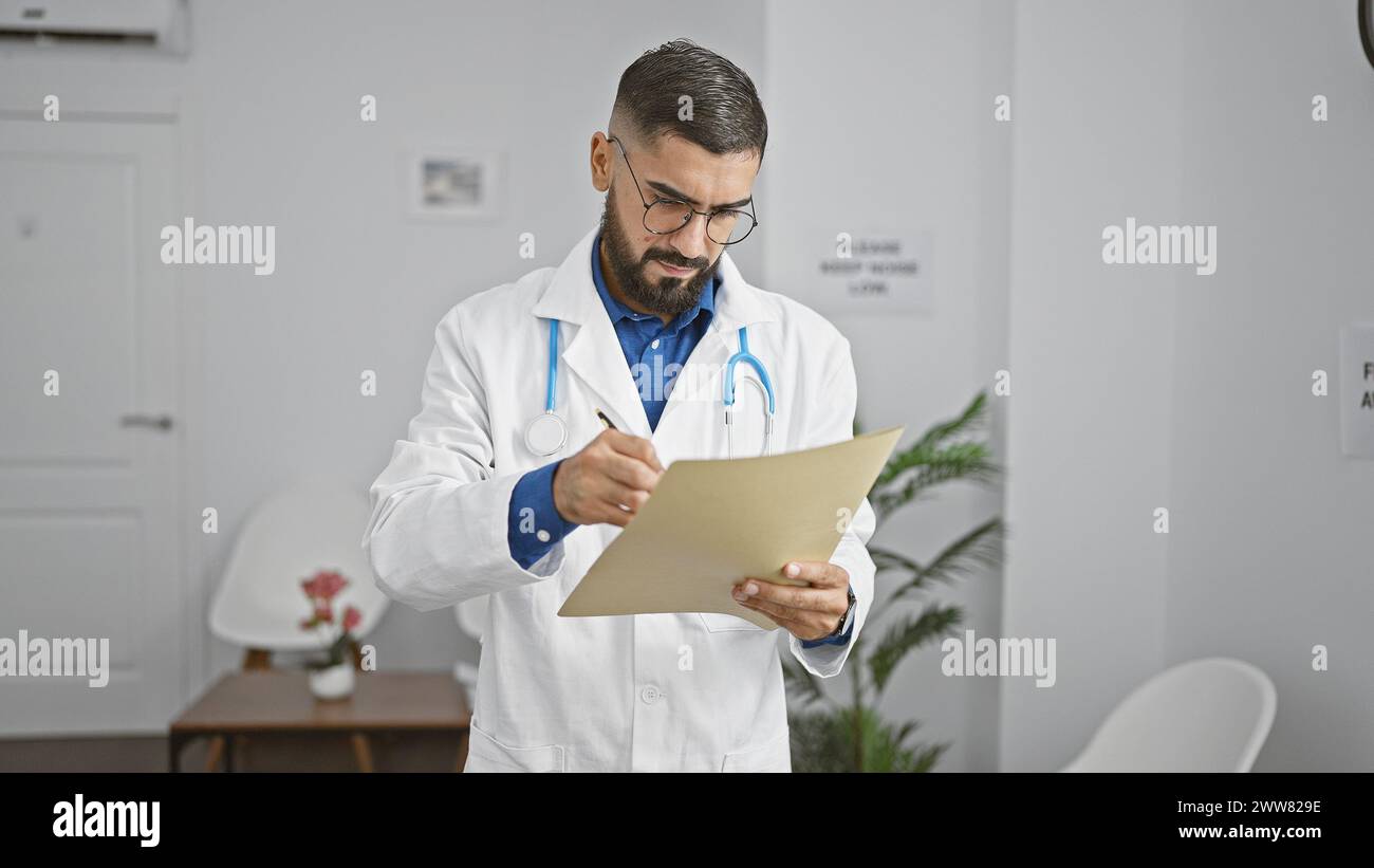 Bearded man in lab coat reviewing documents in a modern clinic's waiting area. Stock Photo