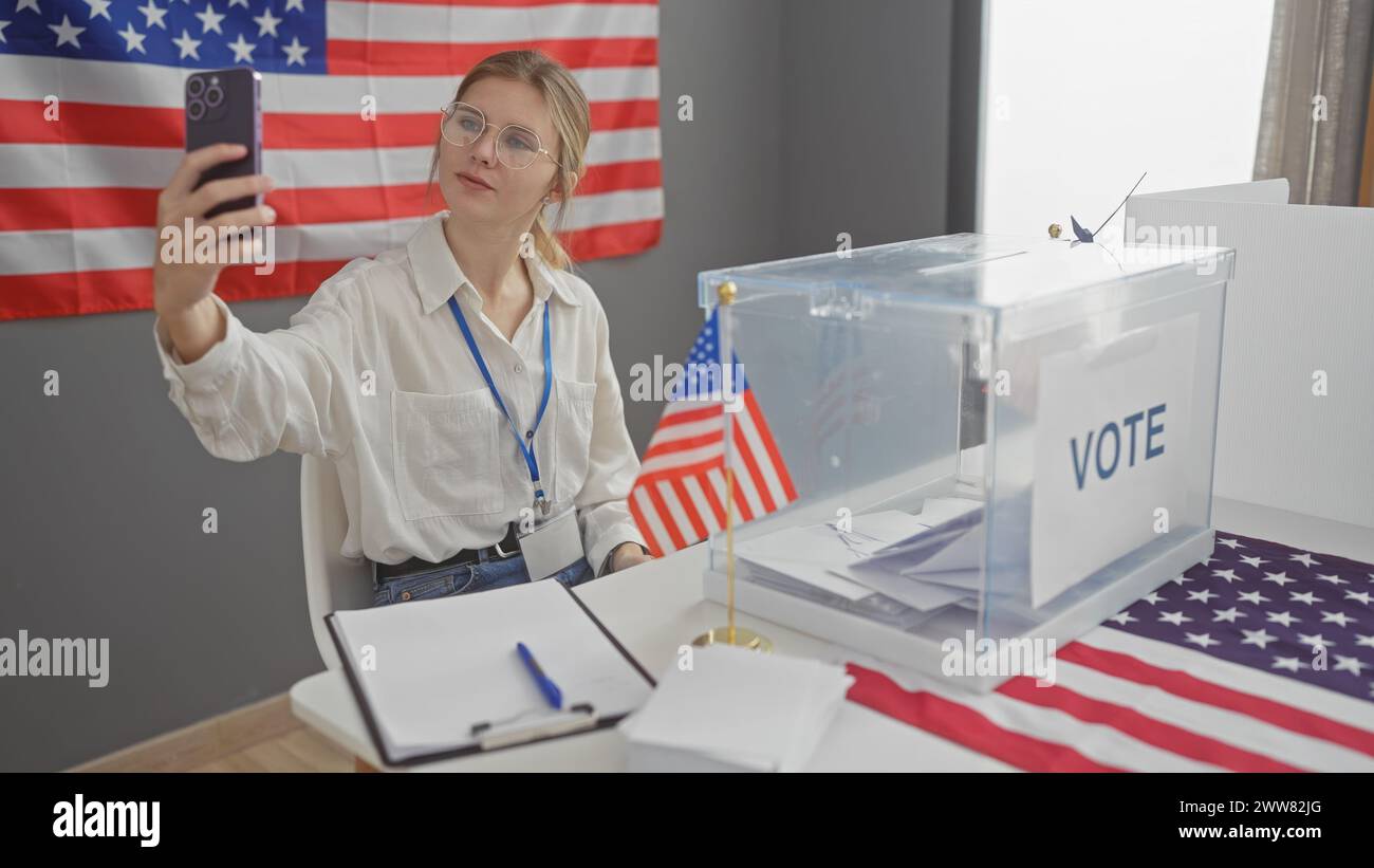 Young woman taking a selfie at a usa voting center, with ballot box and american flag in foreground Stock Photo