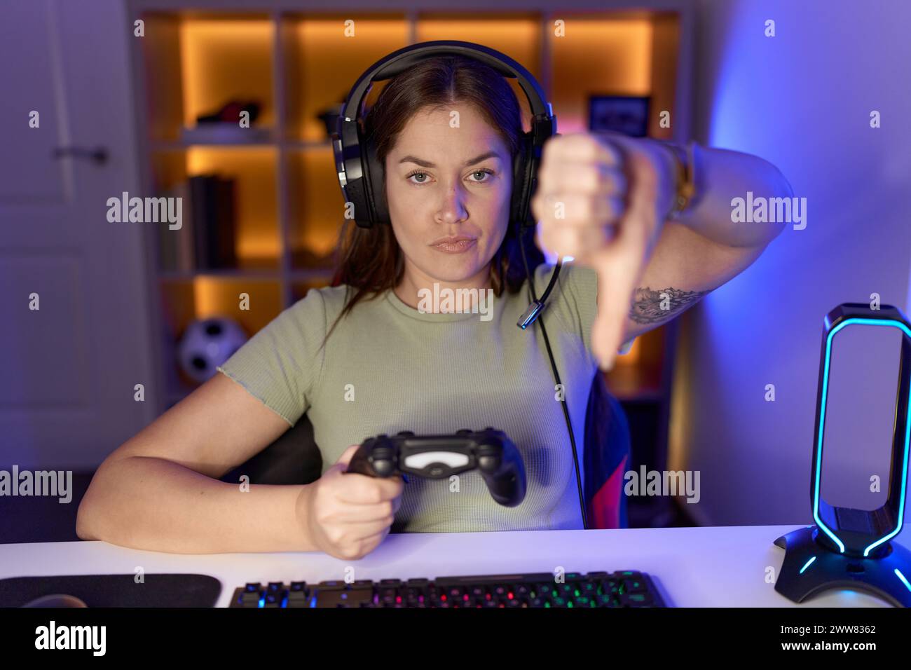 Beautiful brunette woman playing video games wearing headphones looking ...