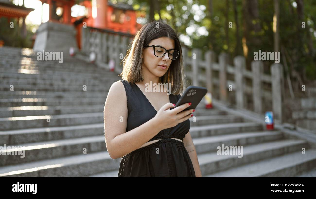 Beautiful hispanic woman in glasses, totally engrossed on her phone ...