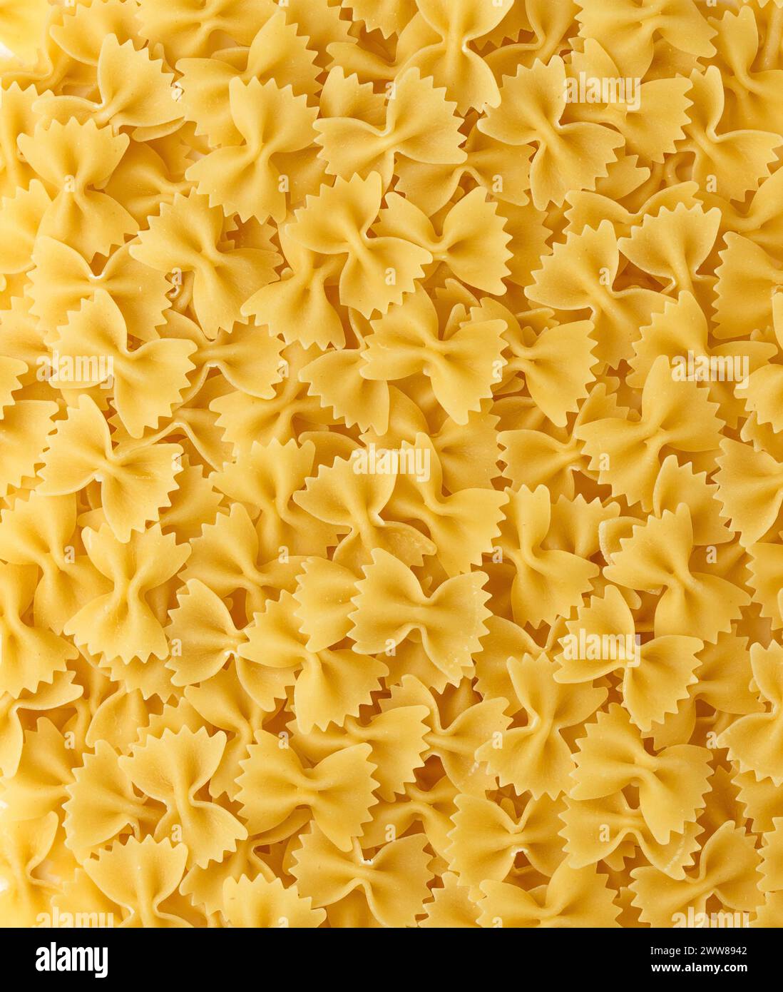 Italian Pasta Farfalle Background. Uncooked Bow Tie Pasta Close-up. Food Creative Concept Stock Photo